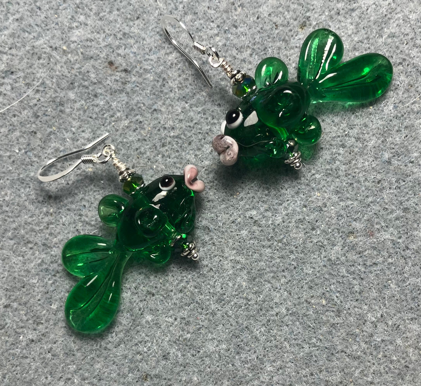 Translucent emerald green lamp work fish bead earrings adorned with emerald green Chinese crystal beads.