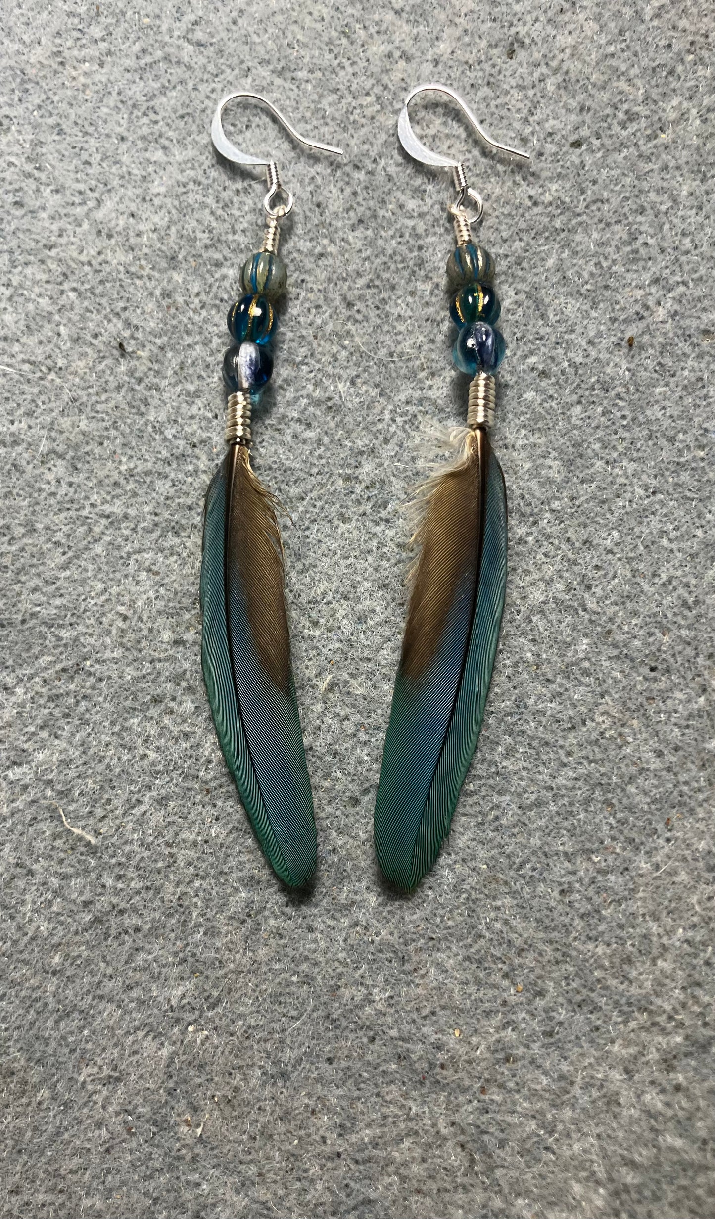 Slender turquoise blue and gold macaw feather earrings adorned with turquoise Czech glass beads.