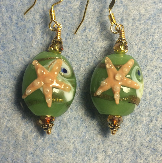 Tan and green lamp work starfish bead earrings adorned with sparkly green Chinese crystal beads.