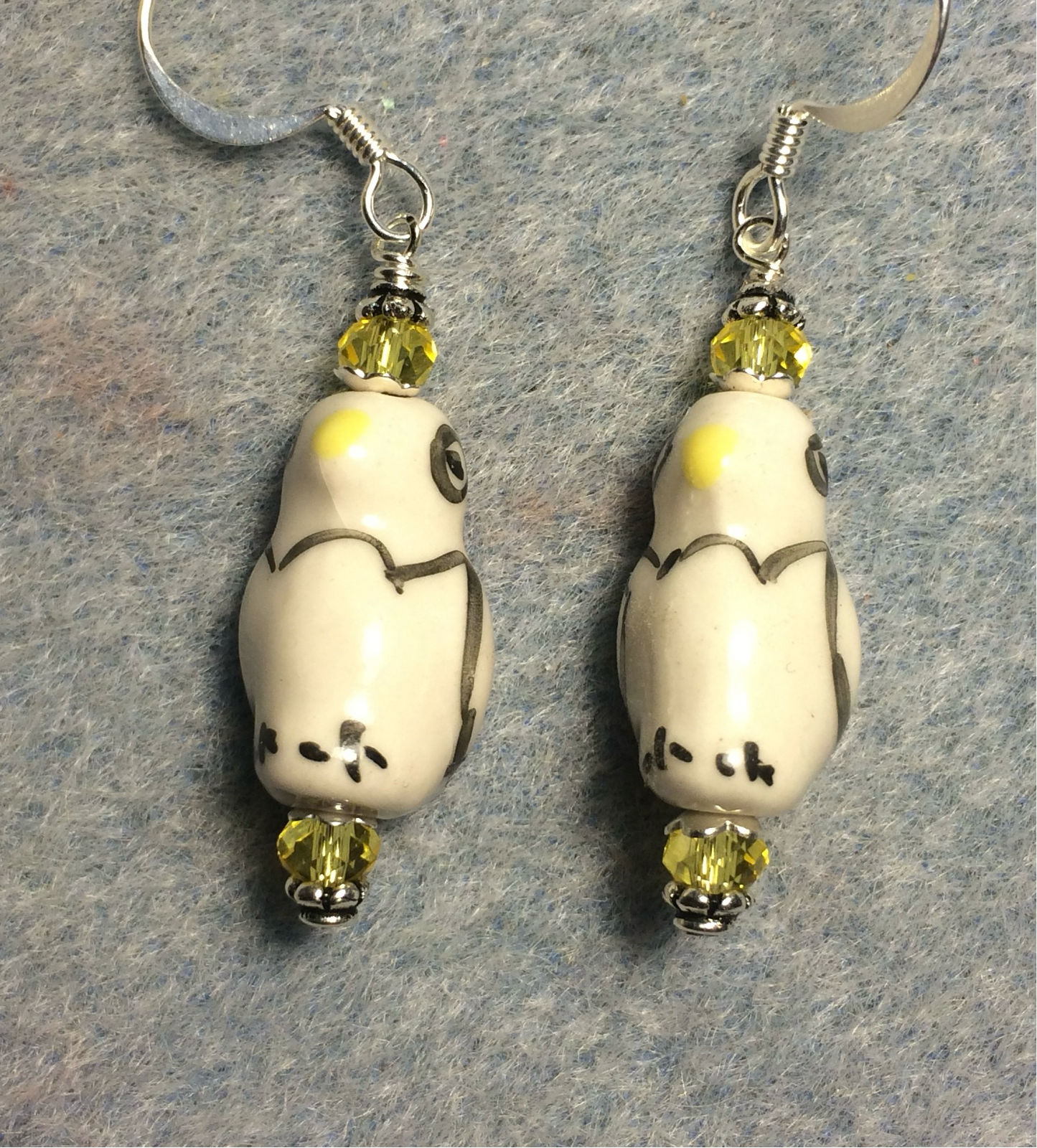 Yellow, black, and white ceramic penguin bead earrings adorned with yellow Chinese crystal beads.