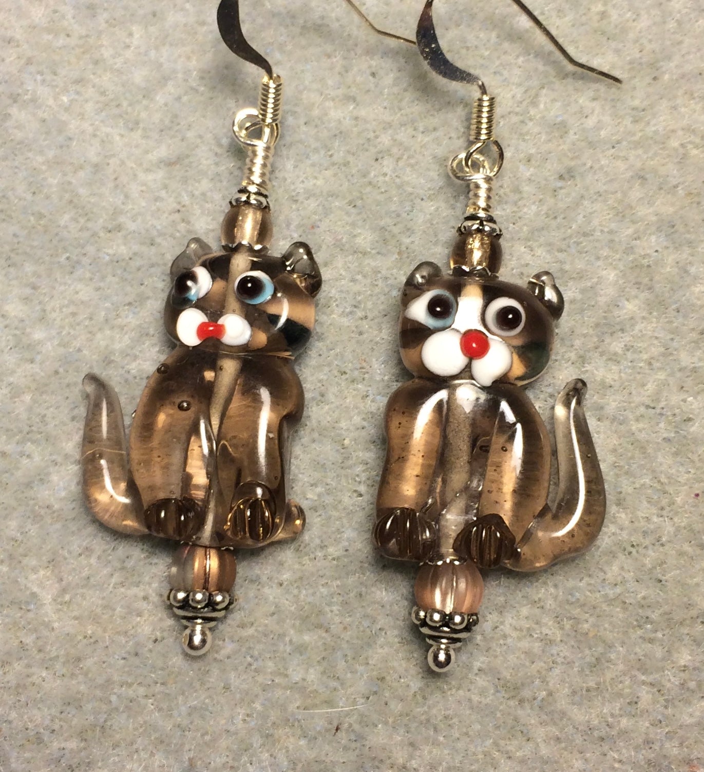 Translucent tan lamp work cat bead earrings adorned with tan Czech glass beads.