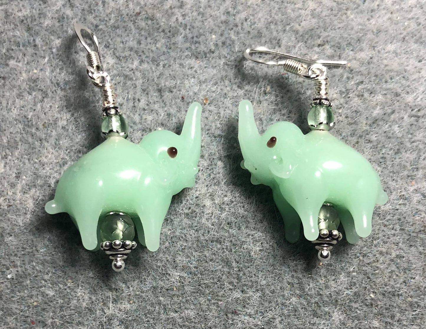 Opaque light green lamp work elephant bead earrings adorned with light green Czech glass beads.
