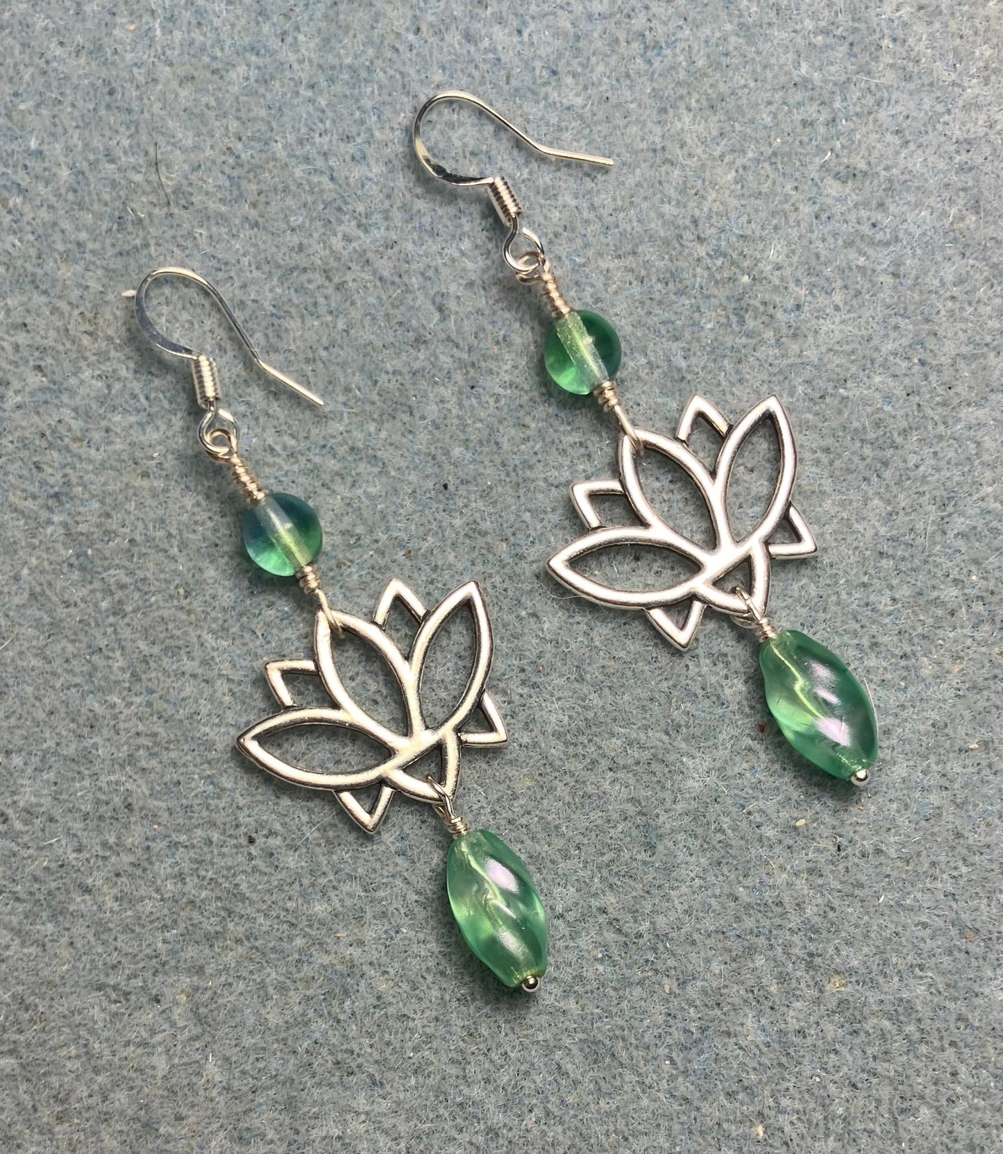 Silver lotus flower connector charm earrings adorned with light green Czech glass drop beads and light green Czech glass beads.