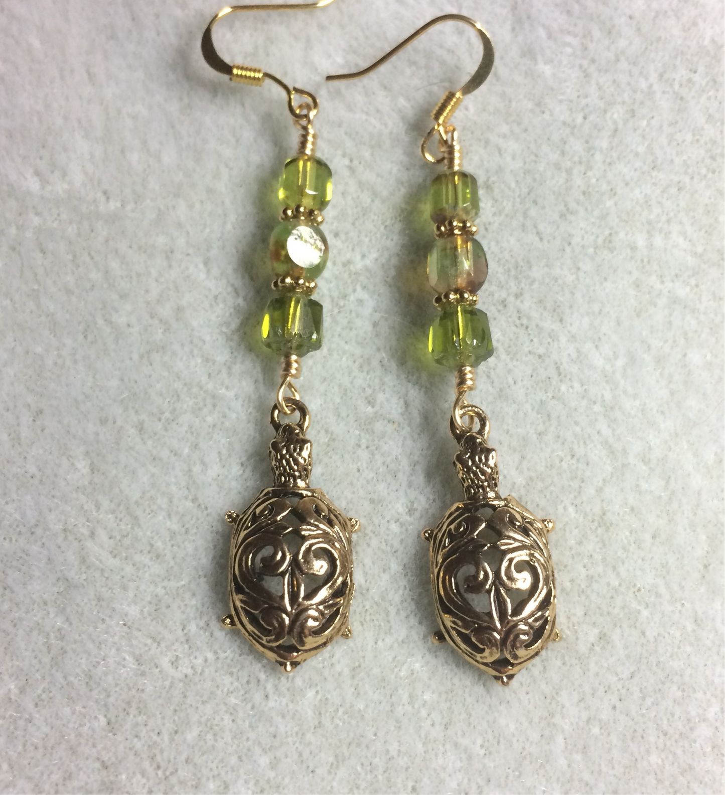 Fancy gold tortoise charm earrings adorned with olive green Czech glass beads