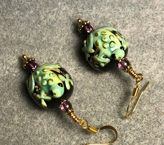 Green and purple lamp work frog bead earrings adorned with purple Czech glass beads.