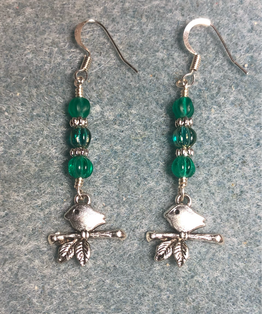 Small silver bird sitting on a branch charm earrings adorned with small teal Czech glass melon beads