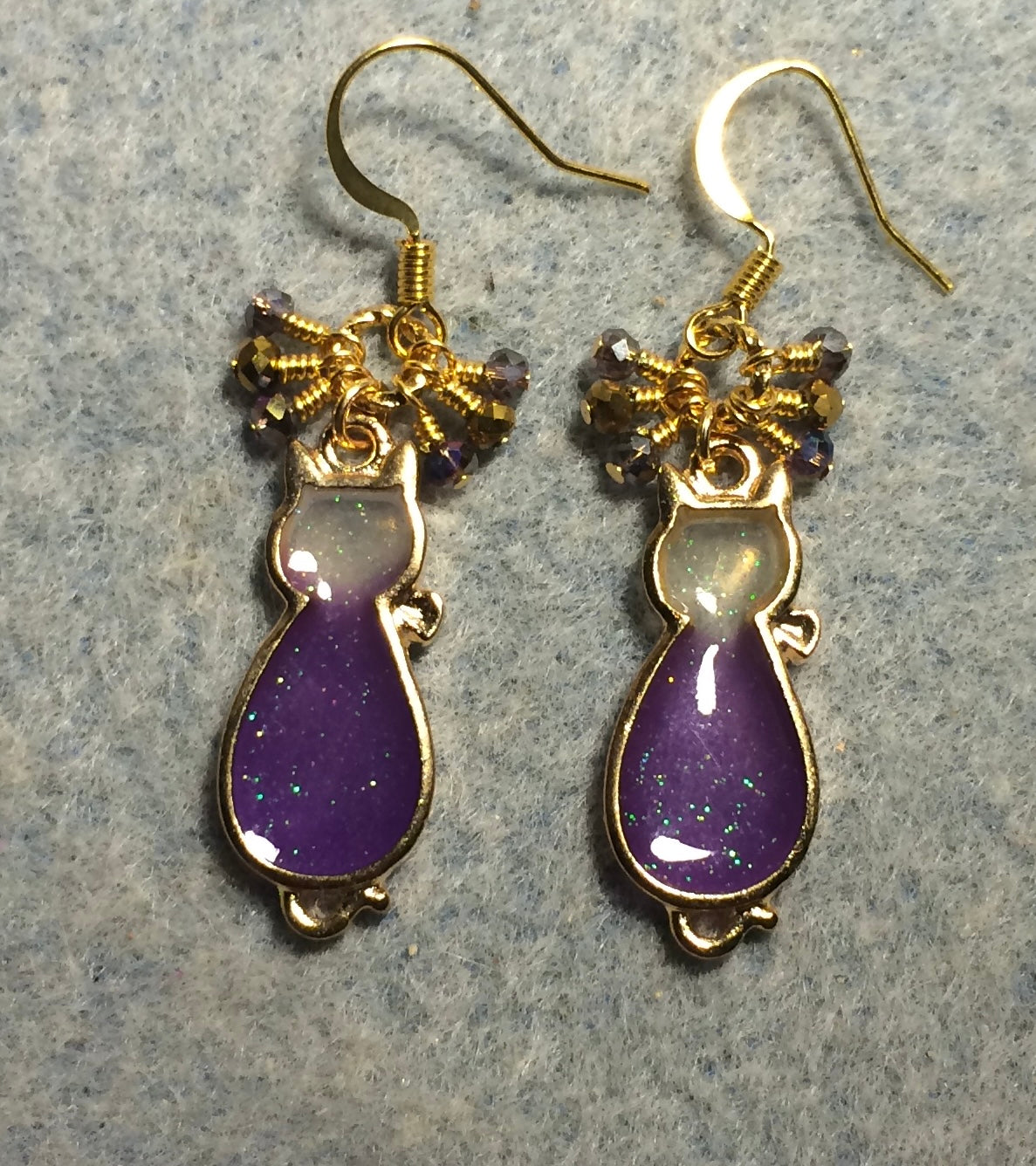 Purple and gold sparkly resin cat charm earrings adorned with small dangling purple and gold Chinese crystal beads.