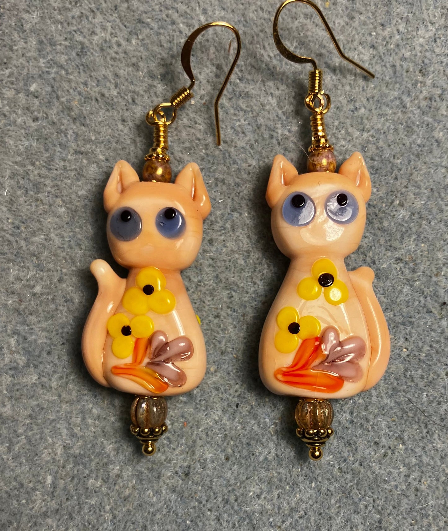 Large beige, orange, and yellow lamp work cat bead earrings adorned with beige Czech glass beads.