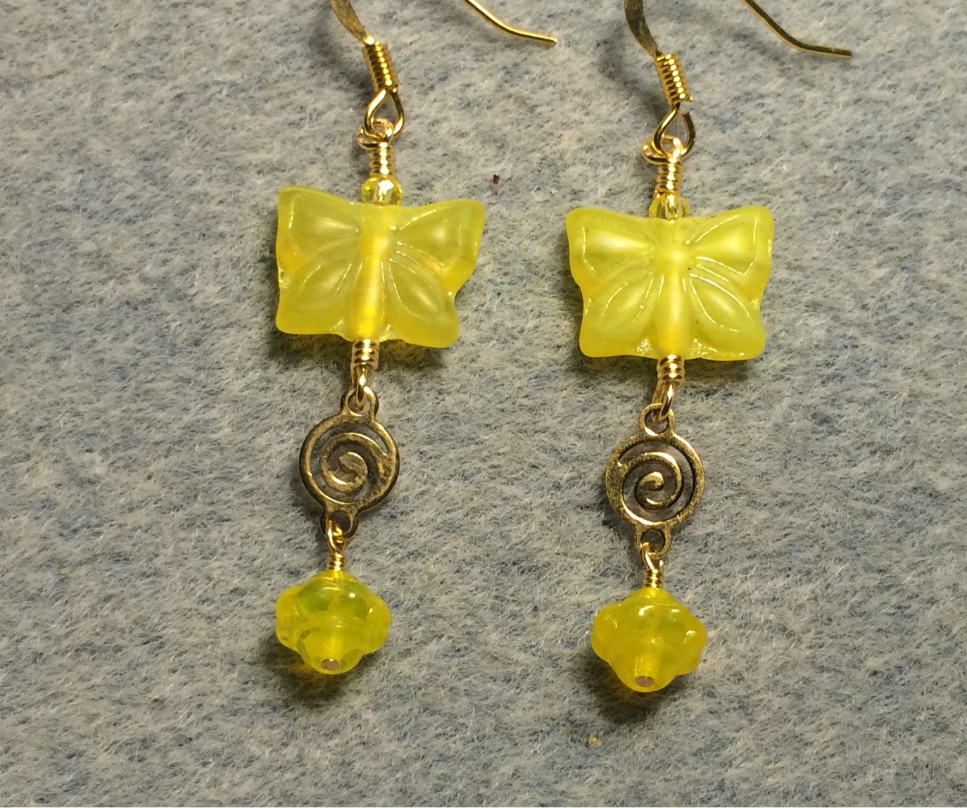 Yellow Czech glass butterfly bead earrings adorned with gold swirly connectors and yellow Czech glass Saturn beads.