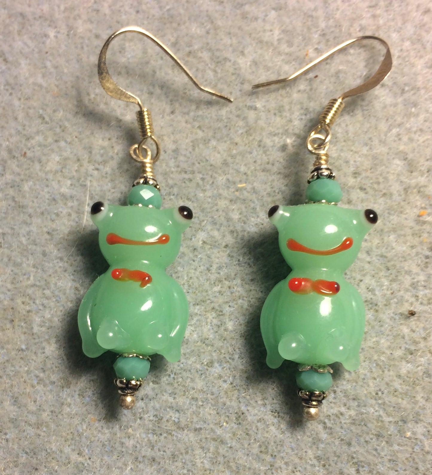 Opaque light green lamp work silly frog bead earrings adorned with light green Chinese crystal beads.