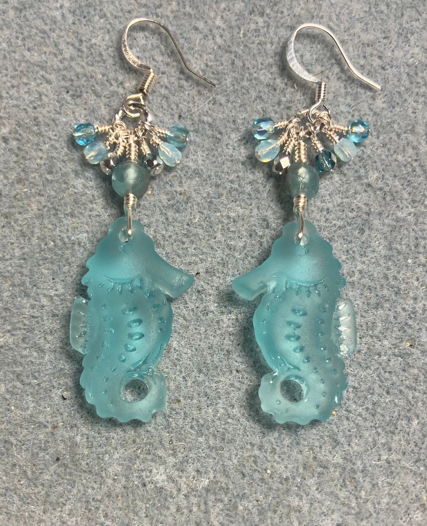 Light turquoise sea glass seahorse pendant bead earrings adorned with light turquoise Czech glass beads and small dangling turquoise Czech glass beads.