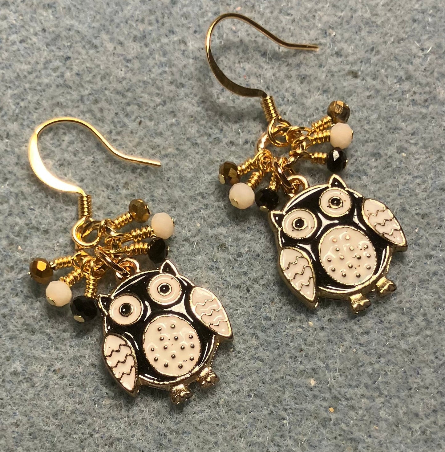 Black, white, and gold enamel owl charm earrings adorned with tiny dangling black, white, and gold Chinese crystal beads.
