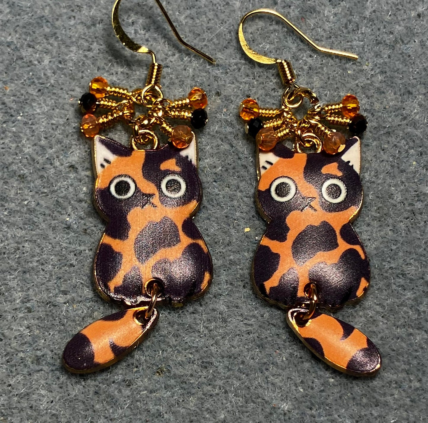 Orange, black, and white enamel calico cat charm earrings adorned with tiny dangling orange and black Chinese crystal beads.