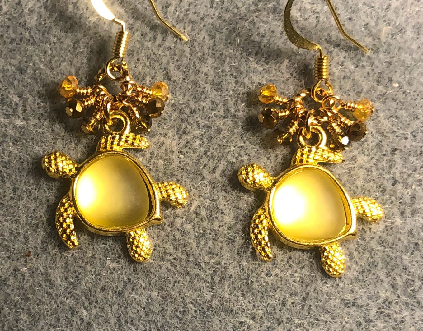 Gold and golden yellow fiber optic sea turtle charm earrings adorned with tiny dangling amber, yellow, and gold Chinese crystal beads.