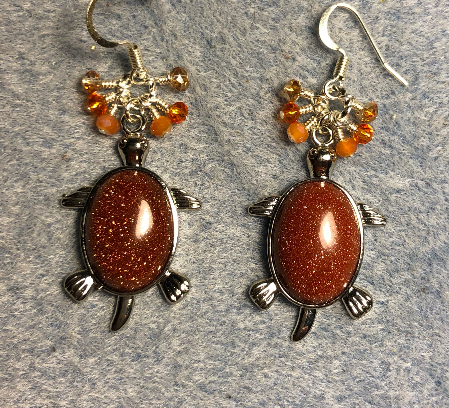 Large silver and orange goldstone gemstone turtle charm earrings adorned with small dangling orange Czech glass beads.