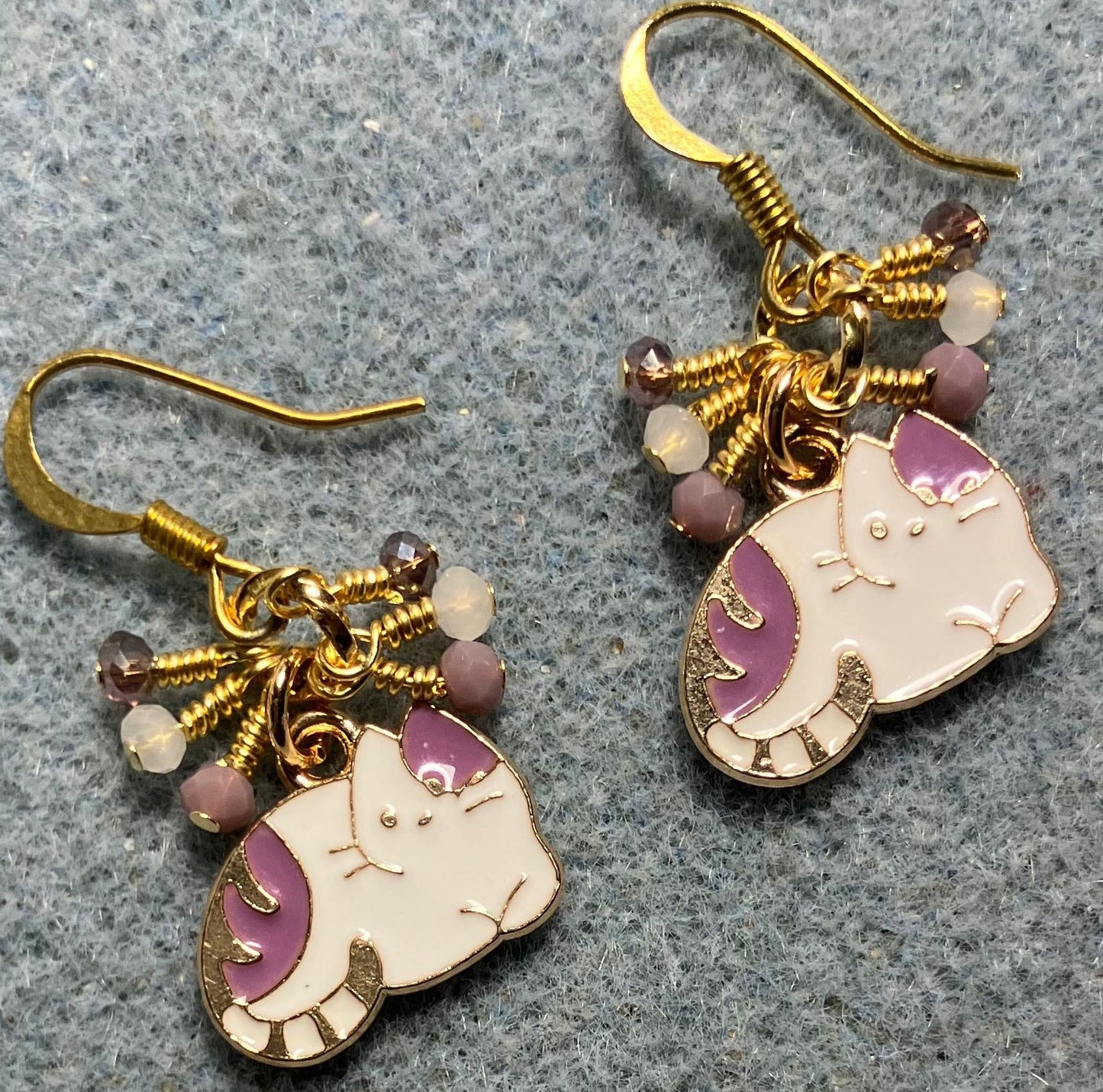 Small violet and white enamel cat charm earrings adorned with tiny dangling violet and white Chinese crystal beads.