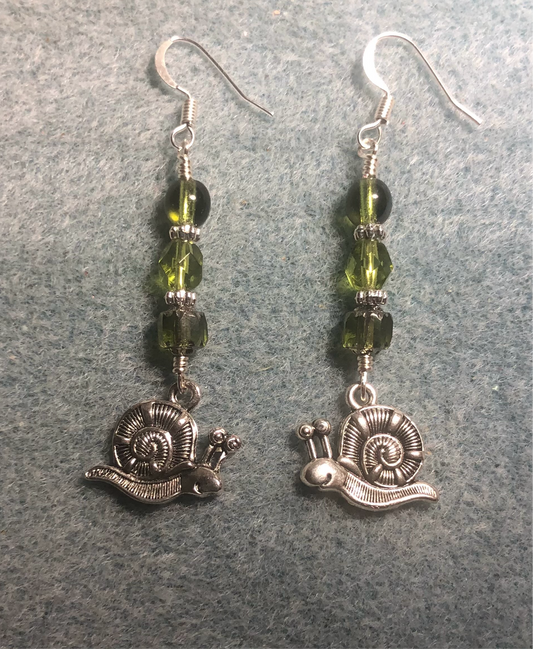 Silver snail charm earrings adorned with olive green Czech glass beads.