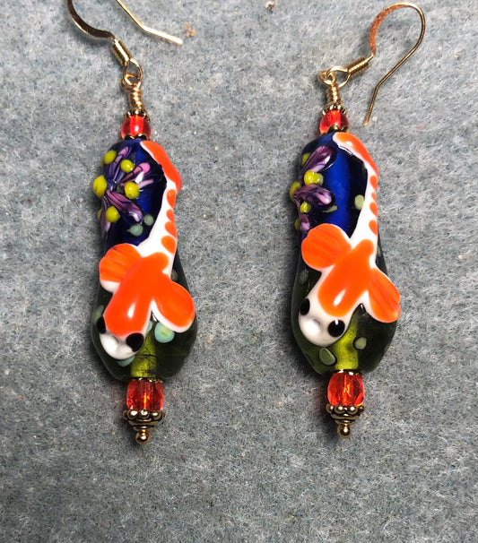 Large orange, green, and blue lamp work koi bead earrings adorned with orange Czech glass beads.