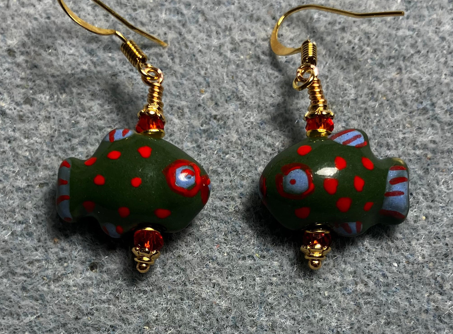 Dark green, red, and blue ceramic spotted fish bead earrings adorned with red Chinese crystal beads.
