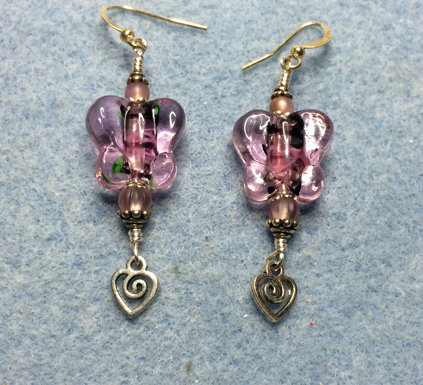 Pink lamp work butterfly bead earrings adorned with pink Czech glass beads and small silver heart charms.