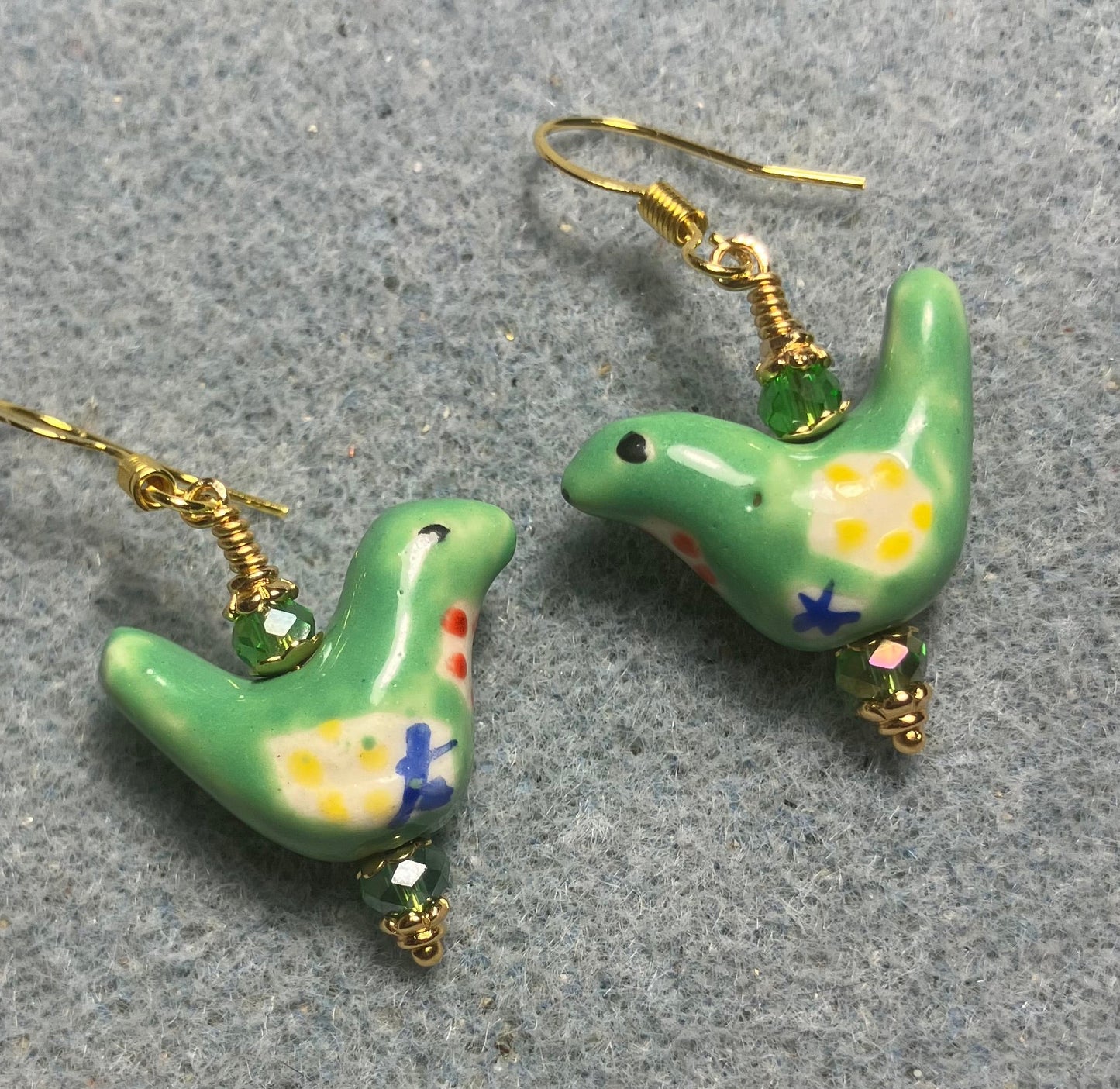 Small green, yellow, and blue ceramic bird bead earrings adorned with green Chinese crystal beads.