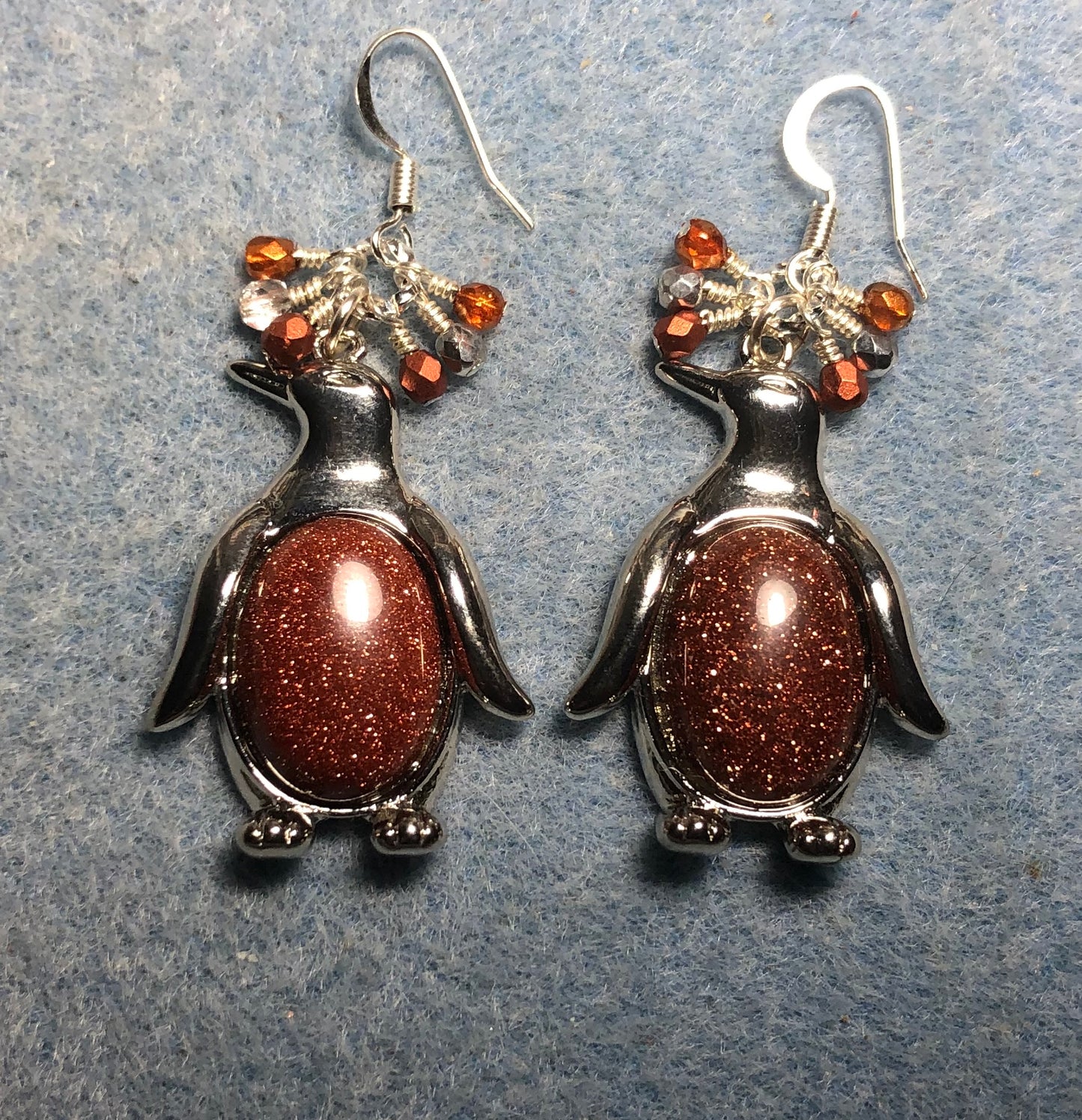 Large silver and orange goldstone gemstone penguin charm earrings adorned with small dangling orange and silver Czech glass beads.