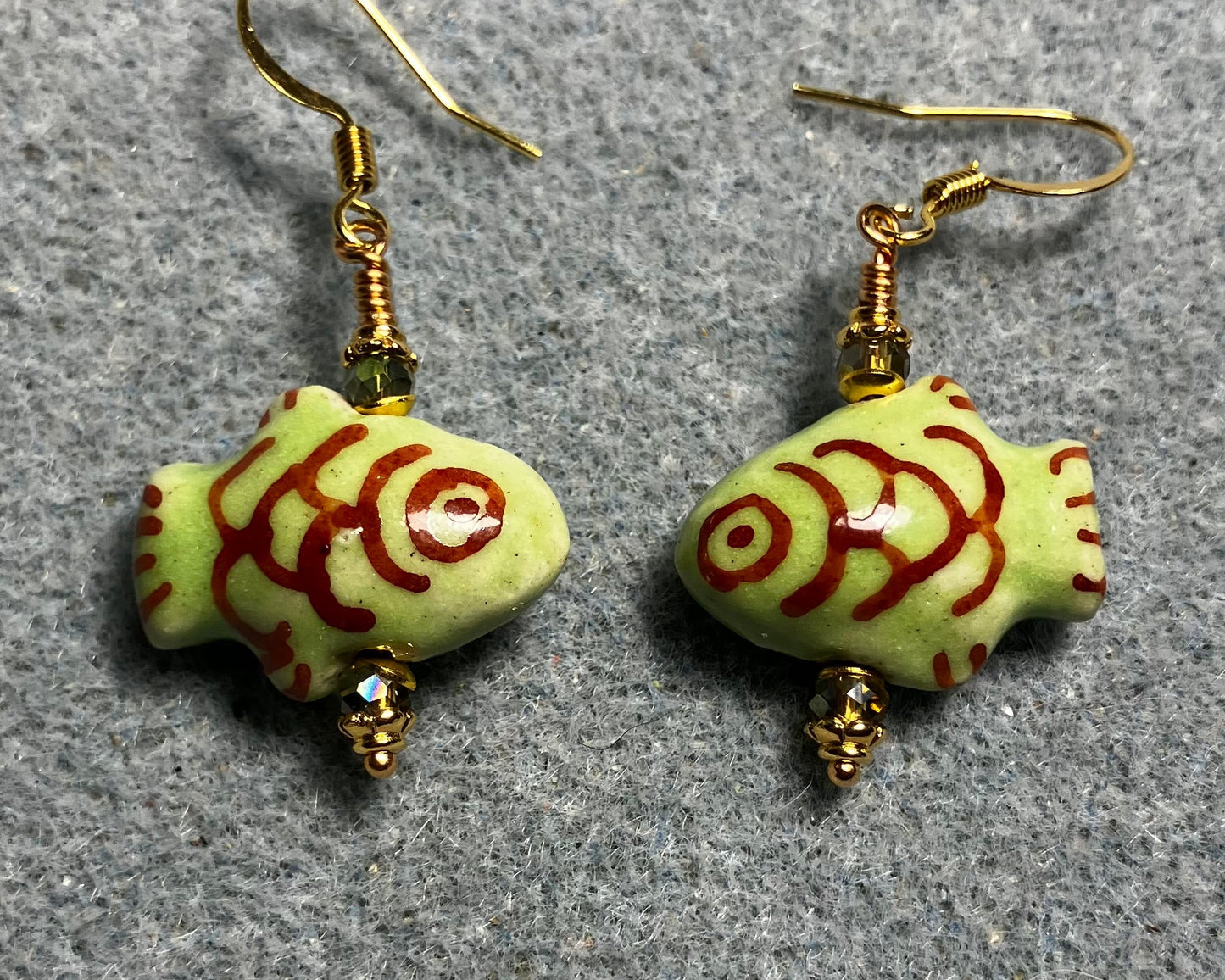 Olive green and dark red ceramic fish bead earrings adorned with sparkly olive green Chinese crystal beads.