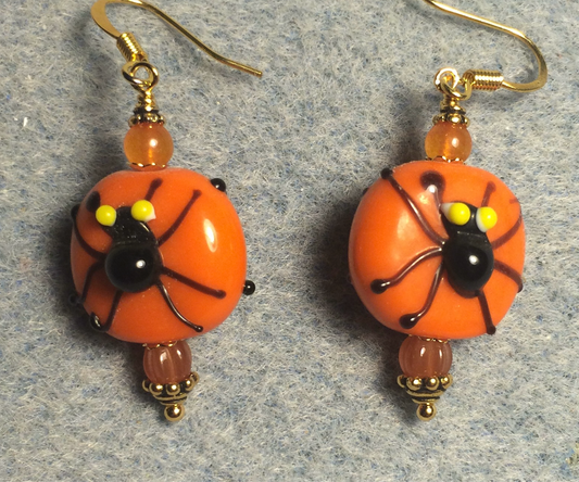 Orange and black lamp work spider bead earrings adorned with orange Czech glass beads.