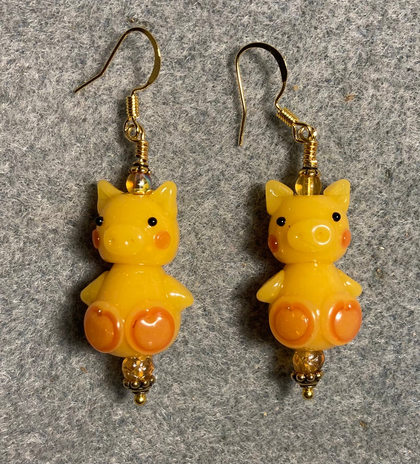 Golden yellow lamp work standing pig bead earrings adorned with amber Czech glass beads.