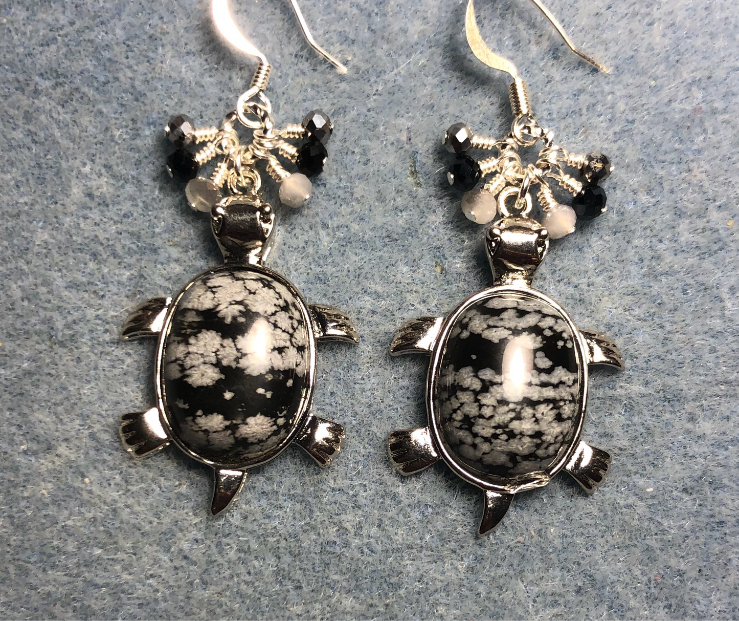 Large silver and snow jasper gemstone turtle charm earrings adorned with small dangling white, black, and silver Czech glass beads.