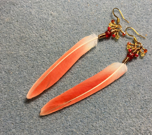 Small bright red sun cheeked conure feather earrings adorned with red Czech glass melon beads and tiny dangling red and yellow Chinese crystal beads.