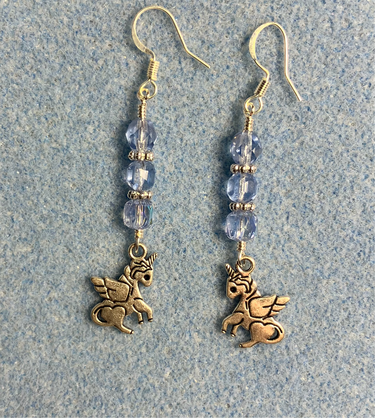 Small silver unicorn charm earrings adorned with light blue Czech glass beads