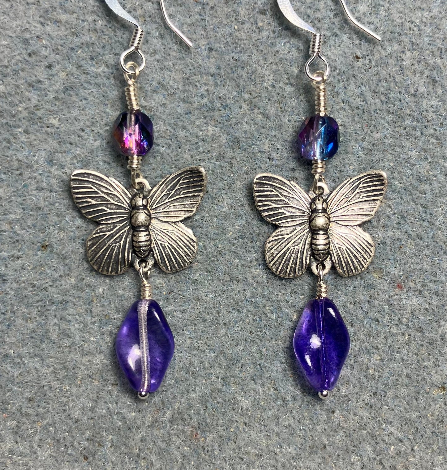 Silver butterfly charm connector earrings adorned with purple Czech glass twist beads and purple Czech glass beads.