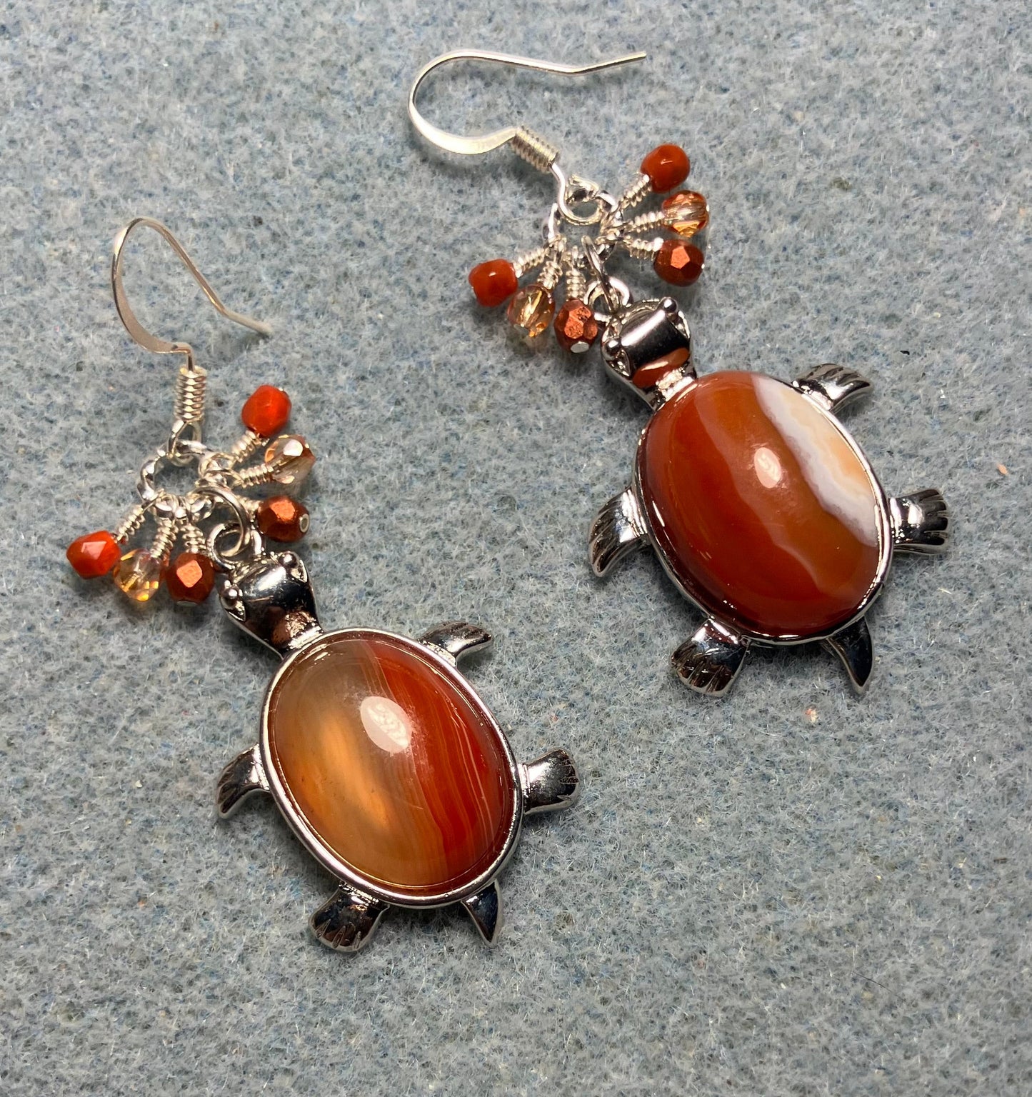 Large silver and red agate gemstone turtle charm earrings adorned with small dangling orange Czech glass beads.