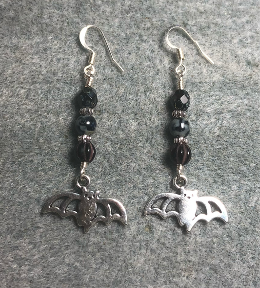 Silver bat charm earrings adorned with black Picasso Czech glass beads.