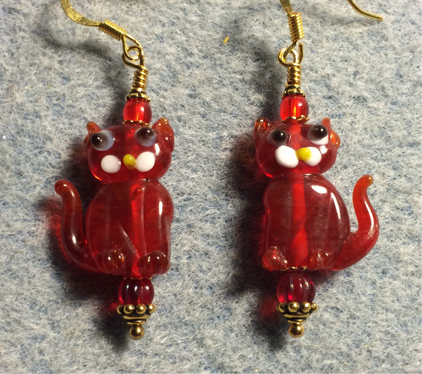 Translucent red lamp work cat bead earrings adorned with red Czech glass beads.
