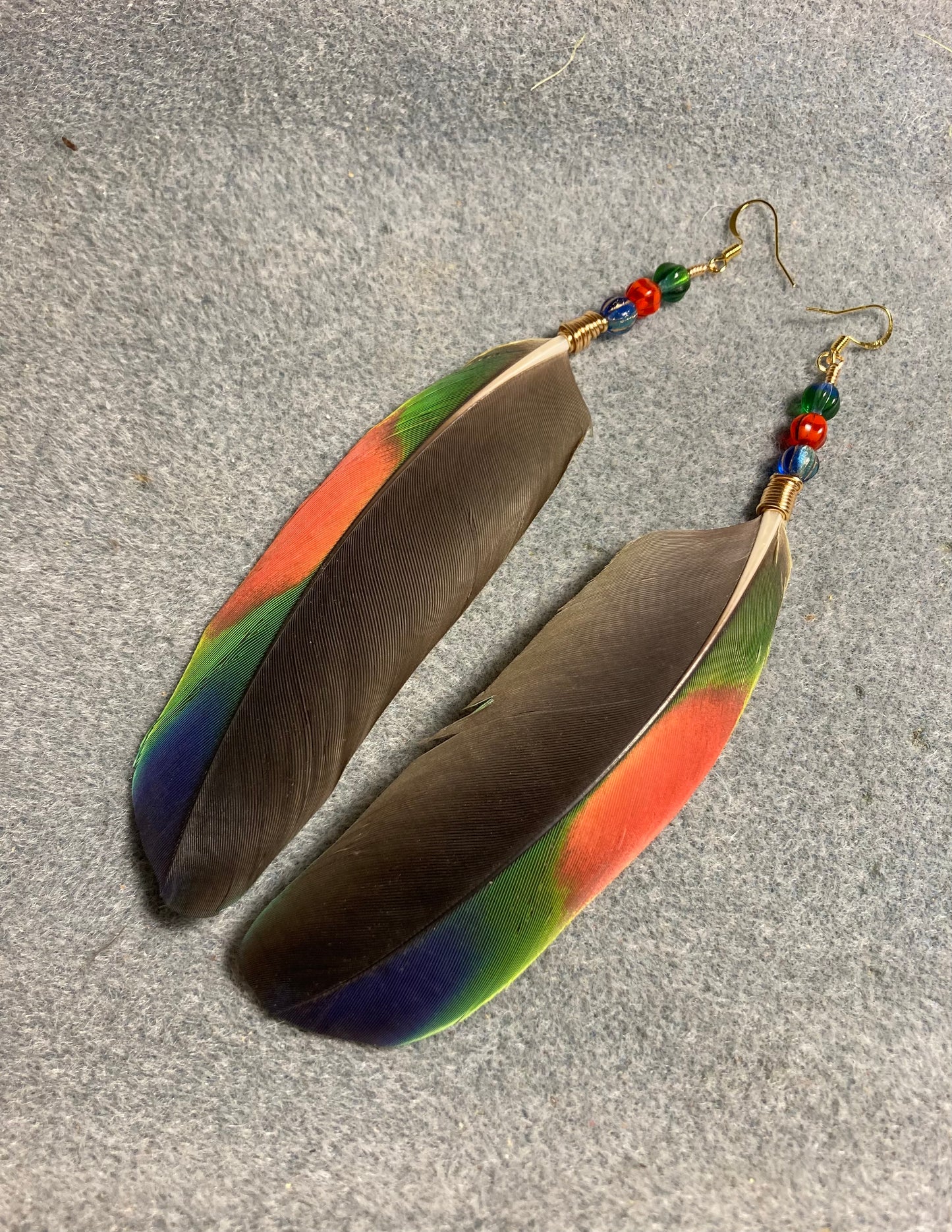 Black, dark blue, red, and green Amazon wing feather earrings adorned with blue, red, and green Czech glass beads.