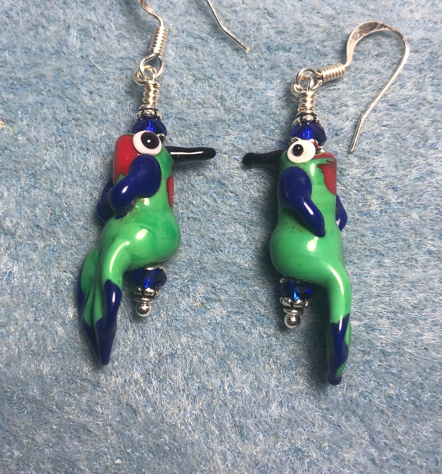 Vintage green, blue, and red lamp work parrot bead earrings adorned with dark blue Chinese crystal beads.