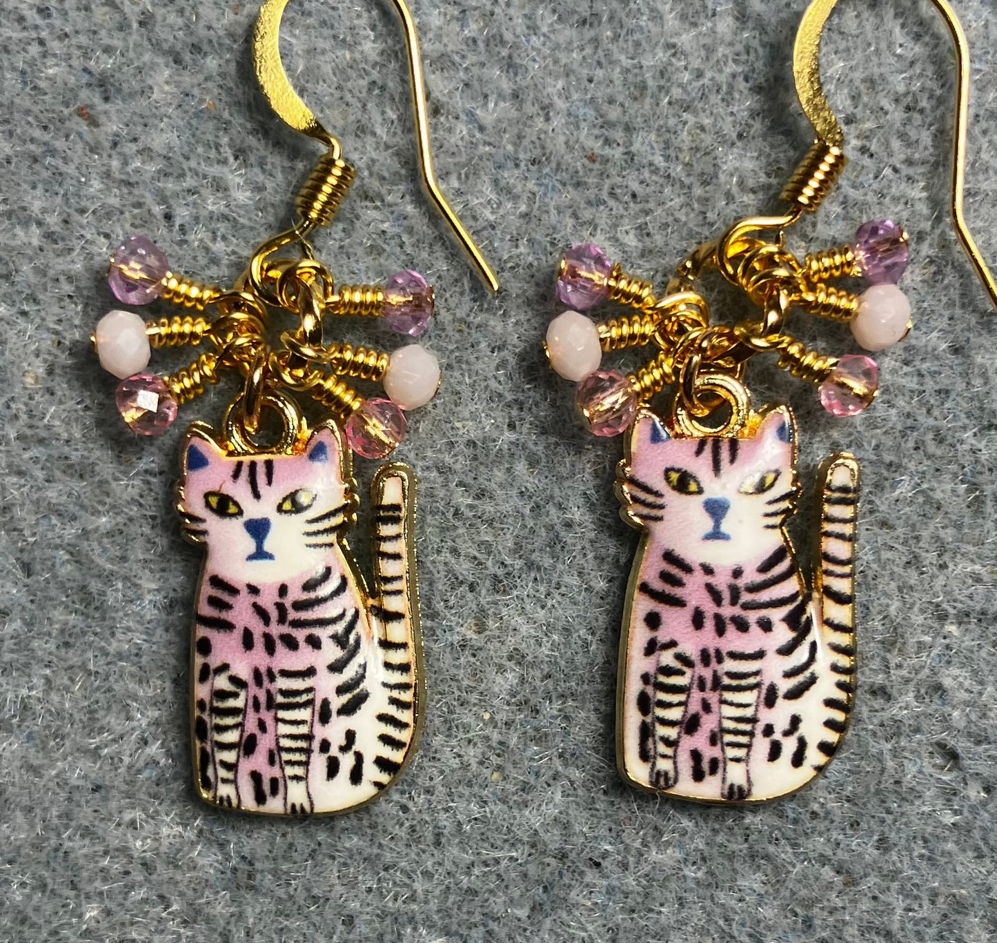 Light pink, black, and white enamel striped cat charm earrings adorned with tiny dangling light pink Chinese crystal beads.