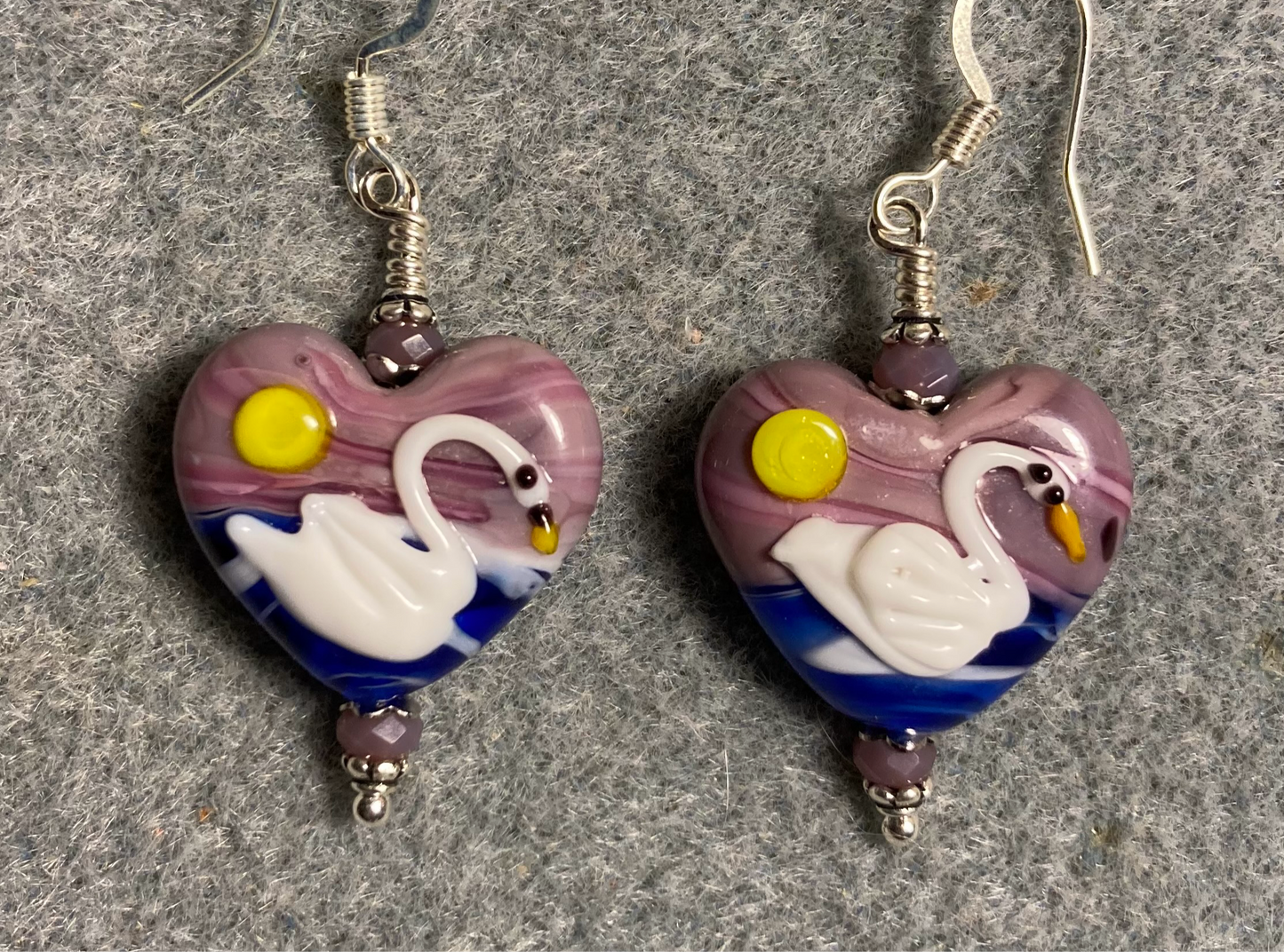 Violet, dark blue, and white heart shaped lamp work swan bead earrings adorned with violet Chinese crystal beads.