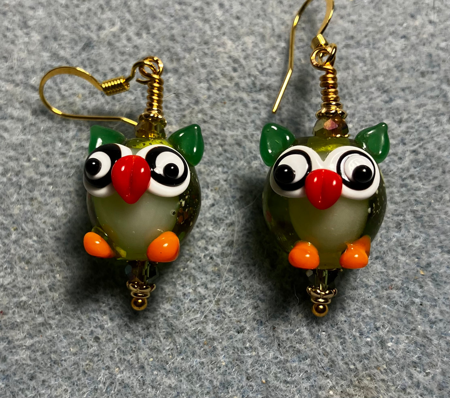 Olive green, orange, and red lamp work owl bead earrings adorned with olive green Chinese crystal beads.
