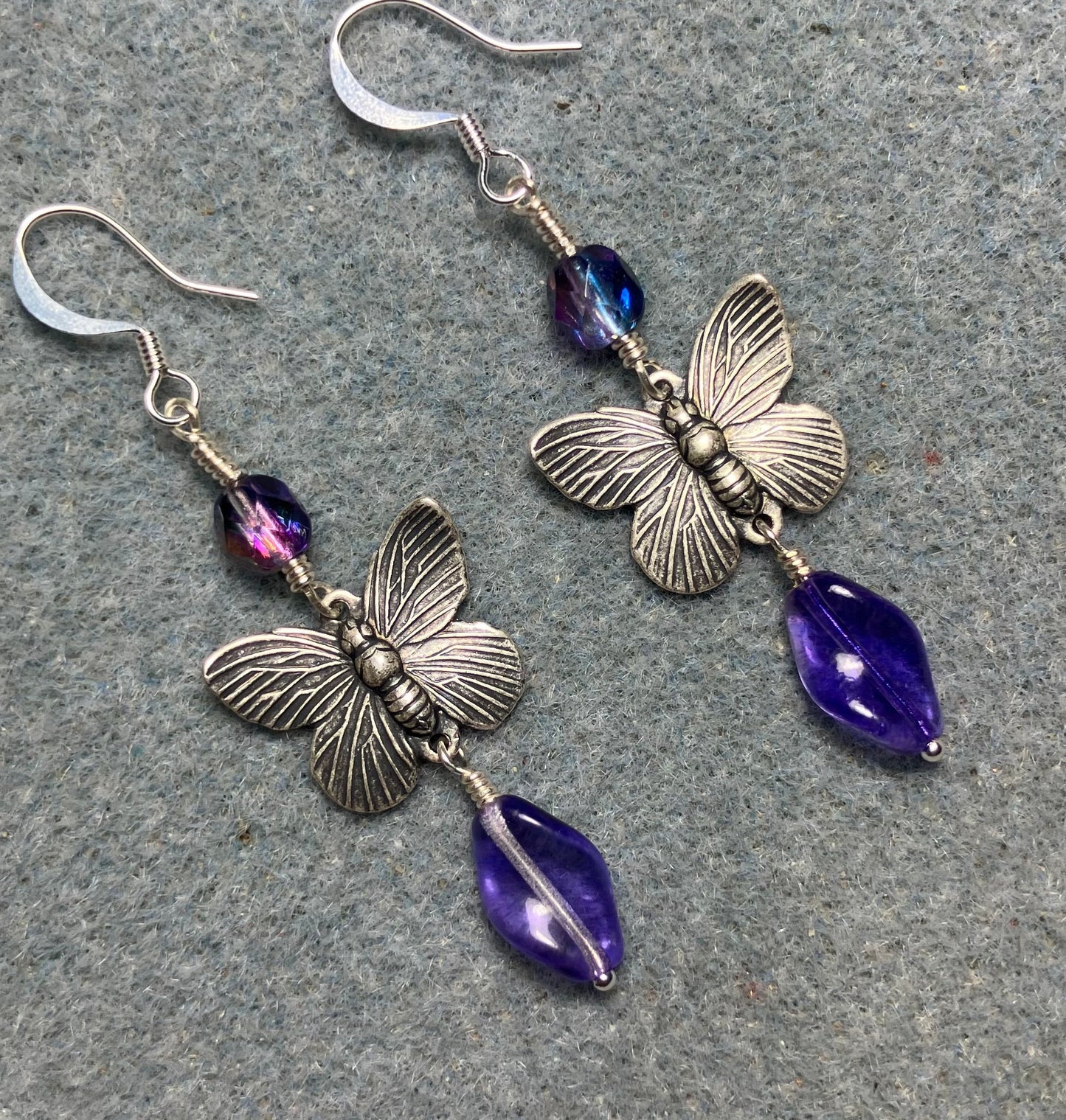 Silver butterfly charm connector earrings adorned with purple Czech glass twist beads and purple Czech glass beads.