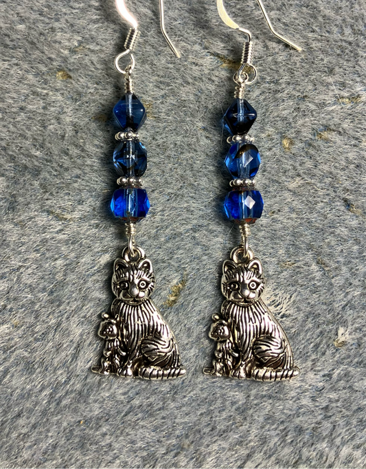 Silver cat charm earrings adorned with blue Czech glass beads.