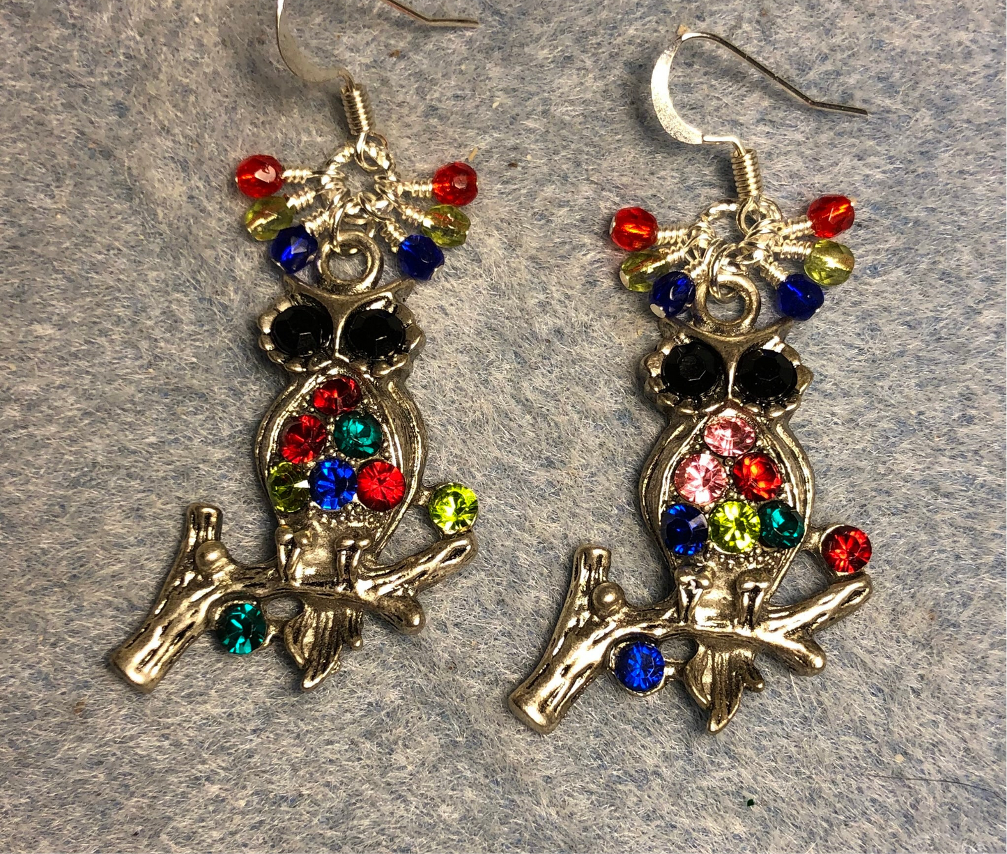 Silver and multicolored rhinestone owl charm earrings adorned with tiny dangling blue, green, and red Czech glass beads.
