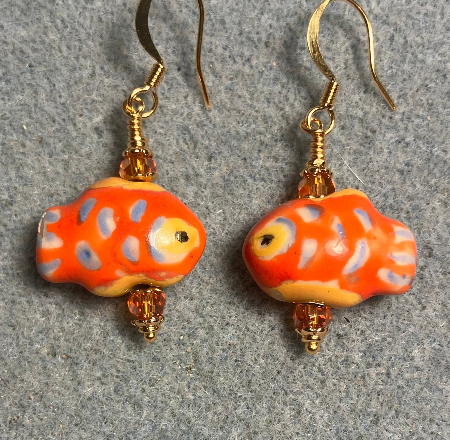 Orange, blue, and yellow ceramic spotted fish bead earrings adorned with orange Chinese crystal beads.