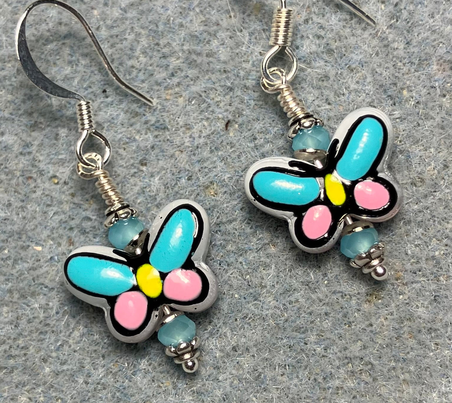 Small turquoise, pink, and yellow ceramic butterfly bead earrings adorned with turquoise Chinese crystal beads.