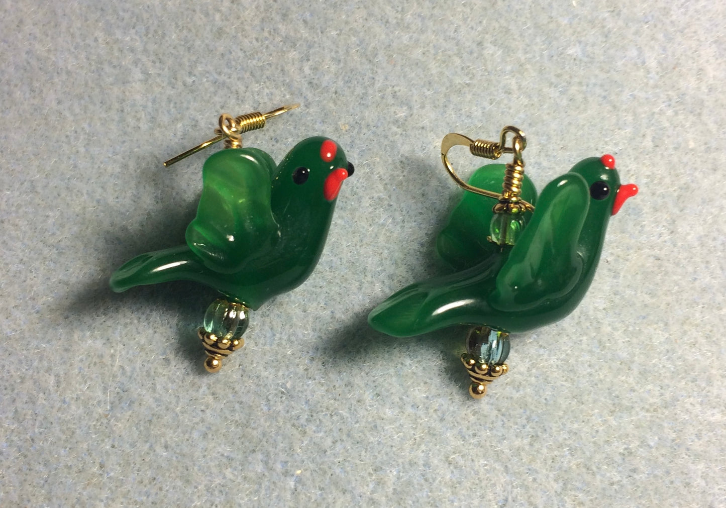Opaque emerald green lamp work flying bird bead earrings adorned with green Czech glass beads.
