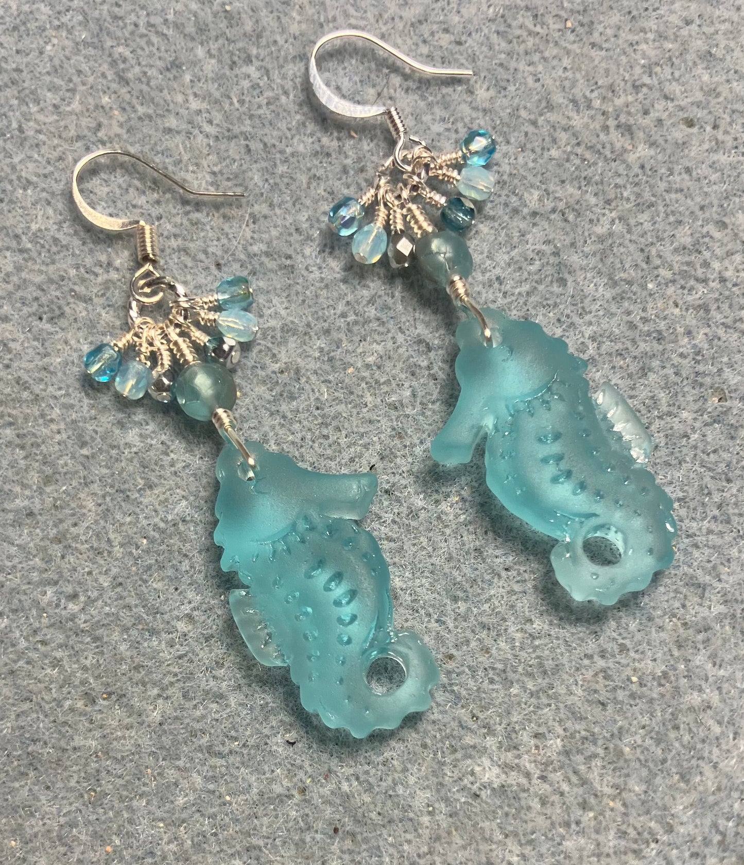 Light turquoise sea glass seahorse pendant bead earrings adorned with light turquoise Czech glass beads and small dangling turquoise Czech glass beads.