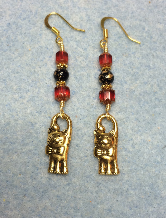 Gold cat charm earrings adorned with red and black Czech glass beads