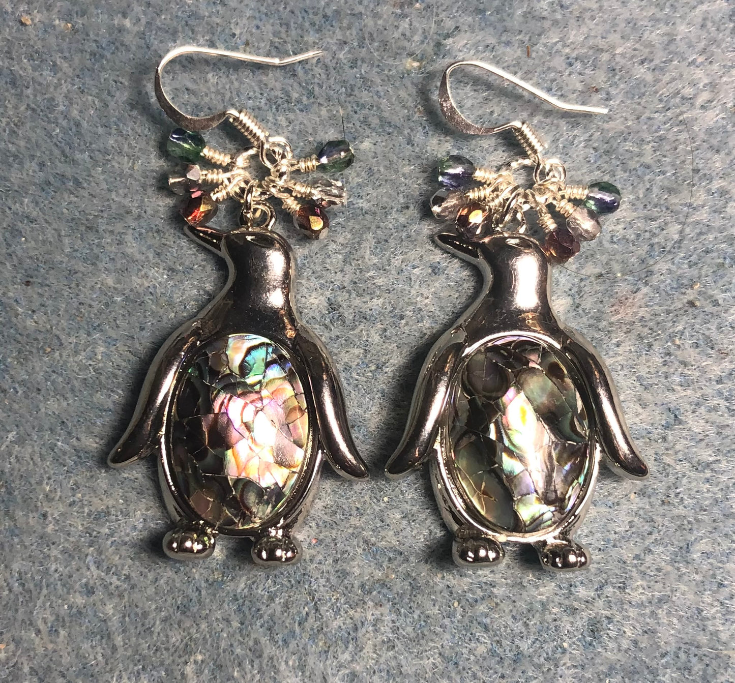 Large silver and abalone penguin charm earrings adorned with small dangling green, silver, and violet Czech glass beads.